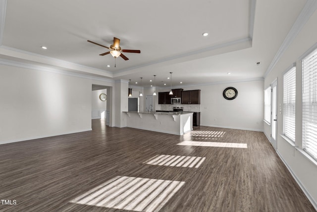 unfurnished living room featuring ceiling fan, dark wood-type flooring, baseboards, ornamental molding, and a tray ceiling