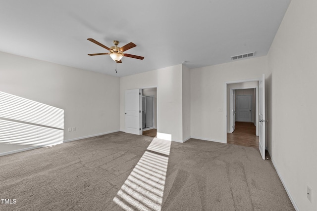 spare room with ceiling fan, carpet floors, visible vents, and baseboards