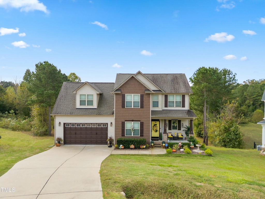 view of front of house featuring a porch, a garage, and a front lawn