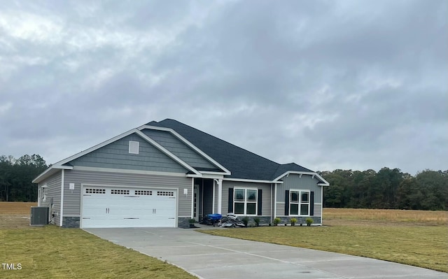 craftsman-style house with central air condition unit, a front lawn, and a garage