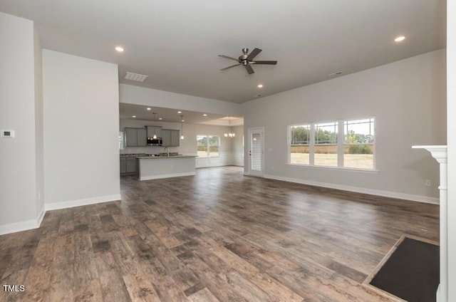 unfurnished living room featuring dark wood-type flooring and ceiling fan