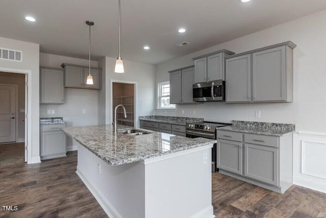 kitchen featuring sink, gray cabinetry, a center island with sink, pendant lighting, and stainless steel appliances