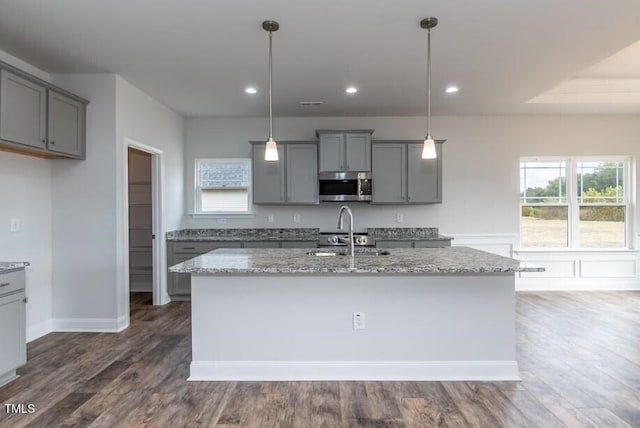 kitchen with sink, gray cabinetry, a kitchen island with sink, and decorative light fixtures