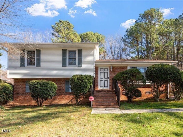 tri-level home with entry steps, brick siding, and a front lawn