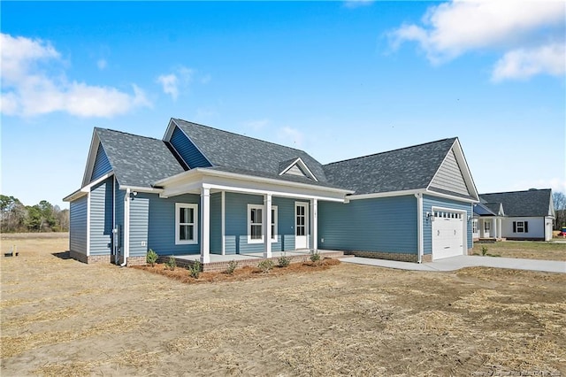 view of front of house featuring a garage, covered porch, driveway, and a shingled roof