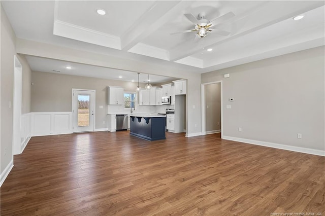 unfurnished living room featuring a ceiling fan, wood finished floors, recessed lighting, beamed ceiling, and a decorative wall