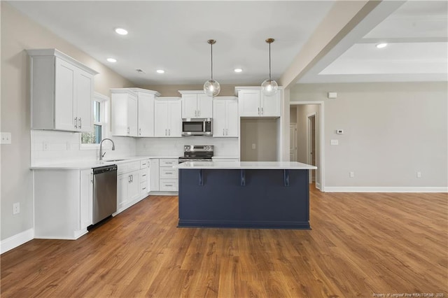 kitchen with a sink, a center island, white cabinetry, and stainless steel appliances