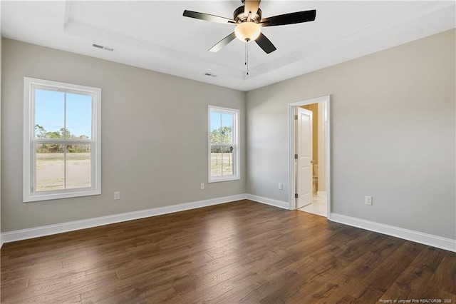 empty room with dark wood finished floors, visible vents, baseboards, and ceiling fan