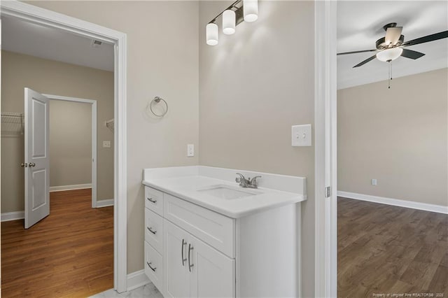 bathroom with baseboards, a ceiling fan, wood finished floors, and vanity