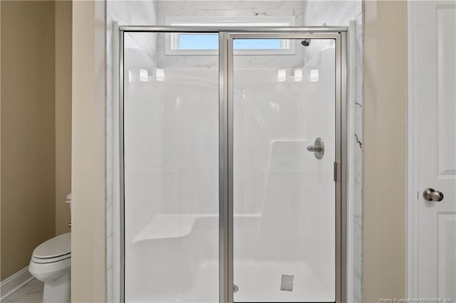 full bathroom featuring a shower stall, toilet, and baseboards