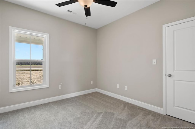 carpeted empty room with visible vents, baseboards, and ceiling fan