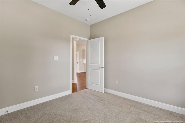 carpeted spare room featuring a ceiling fan and baseboards