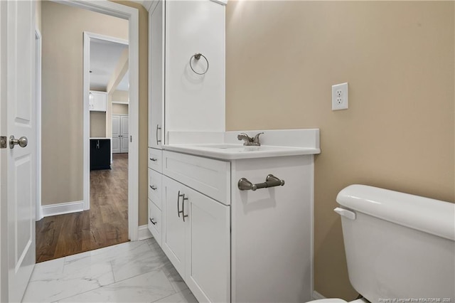 bathroom with baseboards, marble finish floor, vanity, and toilet