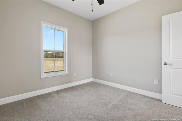 carpeted spare room featuring baseboards and a ceiling fan