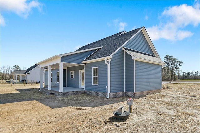 view of side of home featuring roof with shingles and a porch