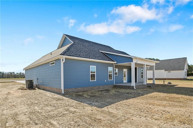 exterior space featuring central AC unit, covered porch, and roof with shingles