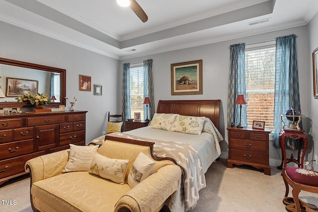 bedroom featuring multiple windows, a tray ceiling, ceiling fan, and crown molding