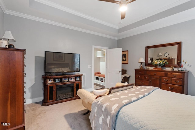 carpeted bedroom with a tray ceiling, ceiling fan, and ornamental molding