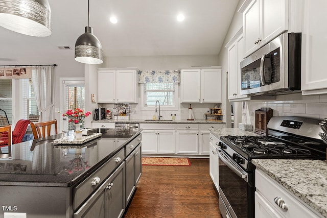 kitchen with white cabinets, appliances with stainless steel finishes, dark stone counters, and sink