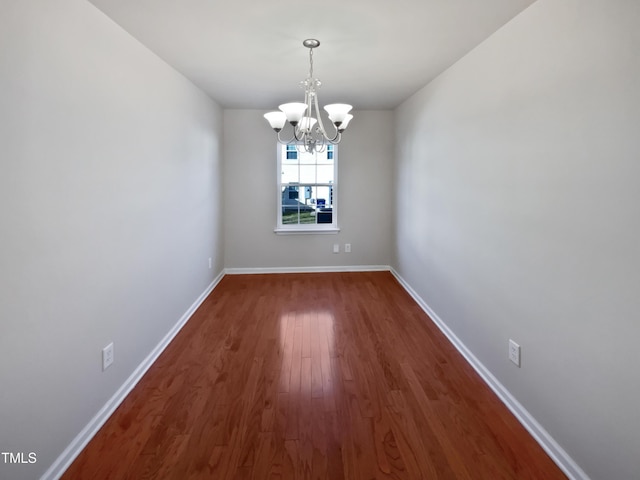 unfurnished dining area with dark hardwood / wood-style floors and an inviting chandelier