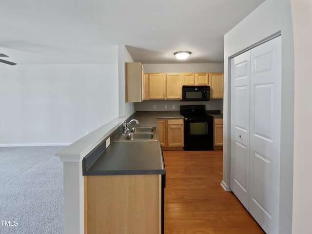 kitchen with kitchen peninsula, light brown cabinetry, light wood-type flooring, sink, and black appliances