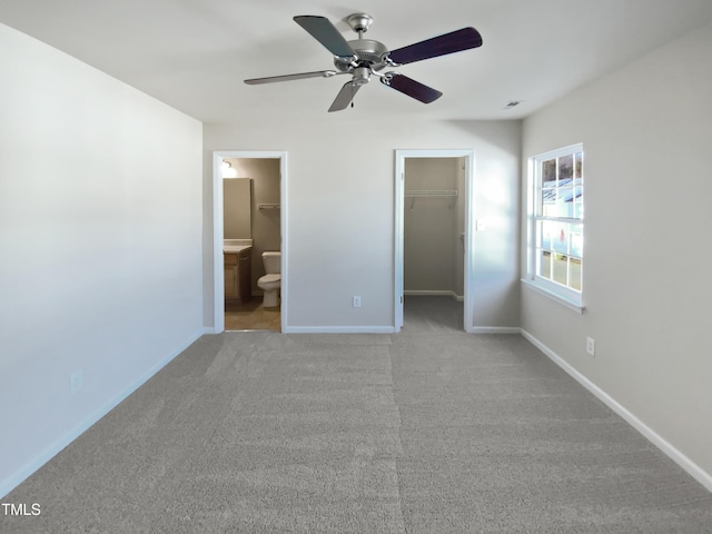 unfurnished bedroom with ensuite bath, ceiling fan, a spacious closet, light colored carpet, and a closet