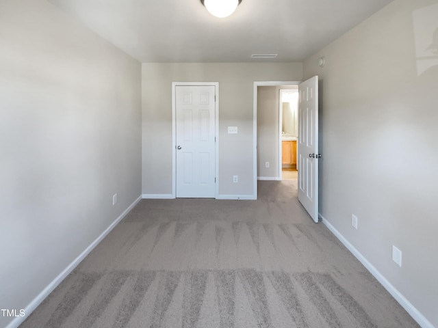 unfurnished bedroom with light carpet and a closet