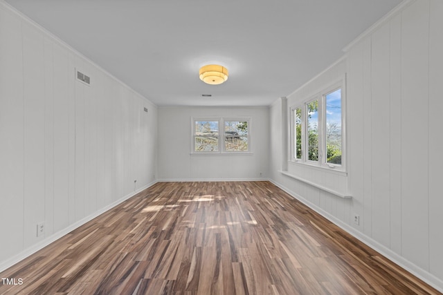 unfurnished room featuring dark hardwood / wood-style flooring, crown molding, and wooden walls