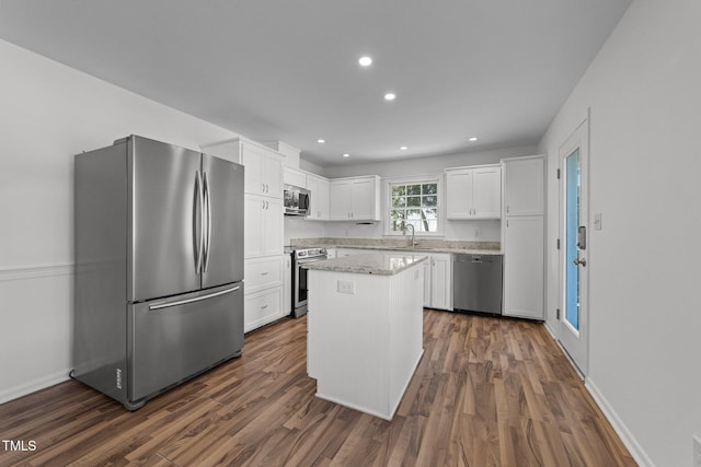 kitchen with sink, a kitchen island, dark hardwood / wood-style floors, white cabinets, and appliances with stainless steel finishes