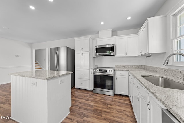 kitchen with light stone counters, sink, white cabinetry, and stainless steel appliances