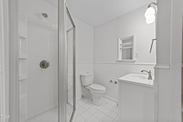 bathroom with tile patterned floors, vanity, toilet, and a shower with door