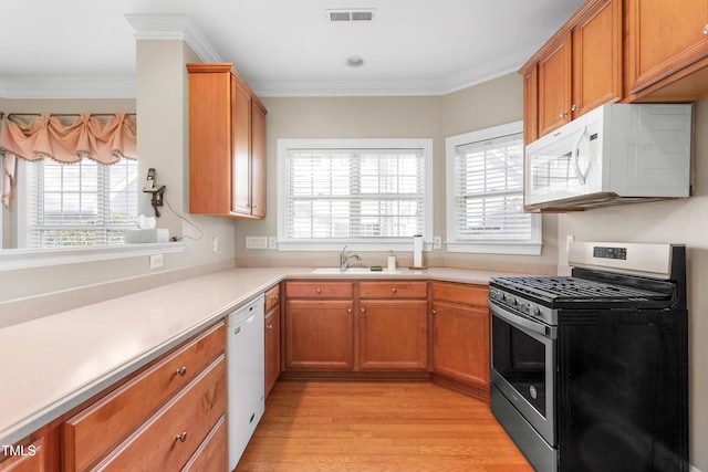 kitchen featuring a wealth of natural light, sink, crown molding, and white appliances