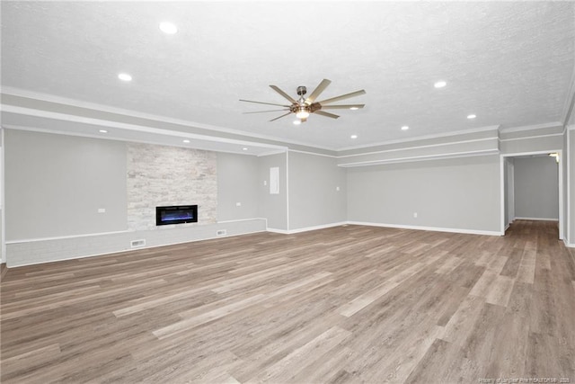 unfurnished living room featuring a stone fireplace, ceiling fan, a textured ceiling, and light wood-type flooring