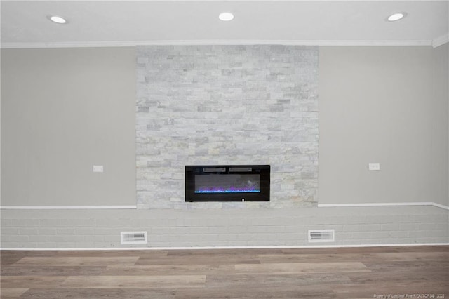 room details featuring crown molding, a large fireplace, and hardwood / wood-style flooring