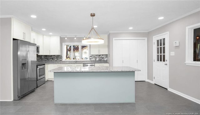 kitchen with a center island, appliances with stainless steel finishes, tasteful backsplash, decorative light fixtures, and white cabinetry