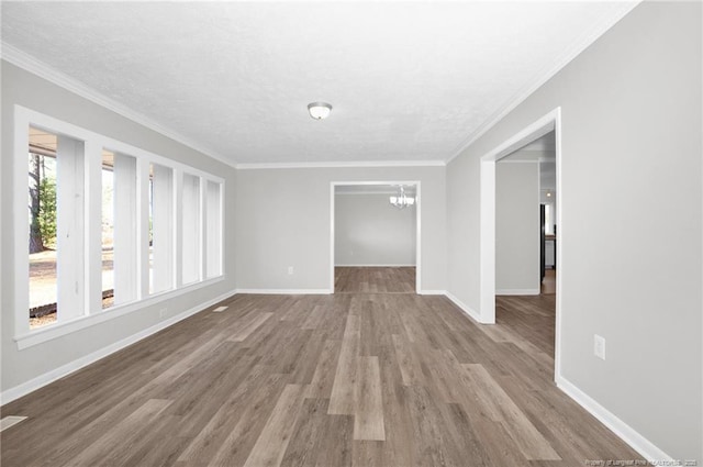 spare room with a chandelier, crown molding, and light hardwood / wood-style floors