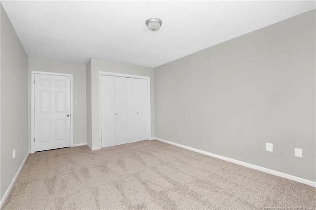 unfurnished bedroom featuring light carpet and a closet