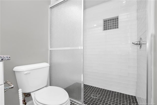 bathroom featuring a tile shower and toilet