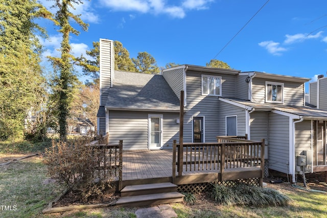 back of house with a shingled roof, a chimney, and a wooden deck