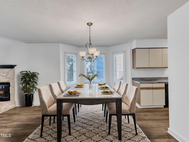 dining space featuring a fireplace, dark hardwood / wood-style flooring, and a chandelier