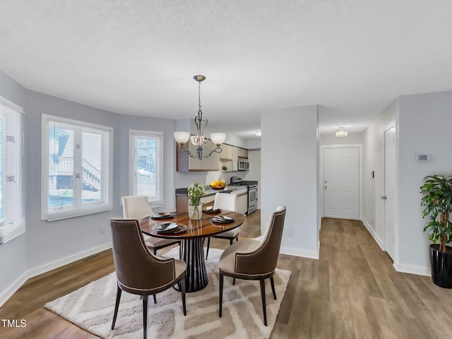 dining area with light wood-type flooring, a notable chandelier, and baseboards