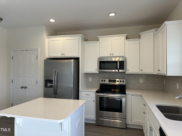 kitchen featuring decorative backsplash, dark hardwood / wood-style flooring, stainless steel appliances, sink, and white cabinets