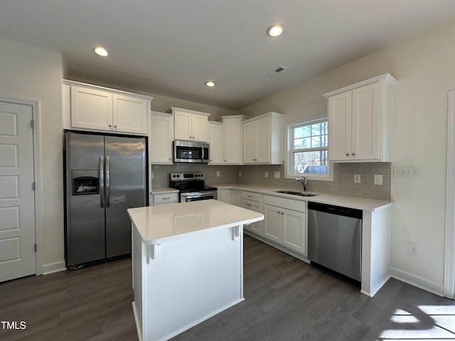 kitchen with white cabinets, sink, appliances with stainless steel finishes, a kitchen island, and dark hardwood / wood-style flooring