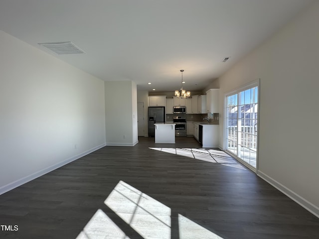 kitchen featuring appliances with stainless steel finishes, a kitchen island, an inviting chandelier, white cabinetry, and hanging light fixtures