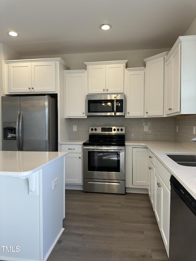 kitchen with white cabinetry, sink, dark wood-type flooring, stainless steel appliances, and decorative backsplash