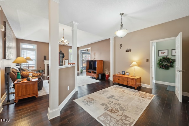 entrance foyer featuring decorative columns, vaulted ceiling, and dark wood-type flooring