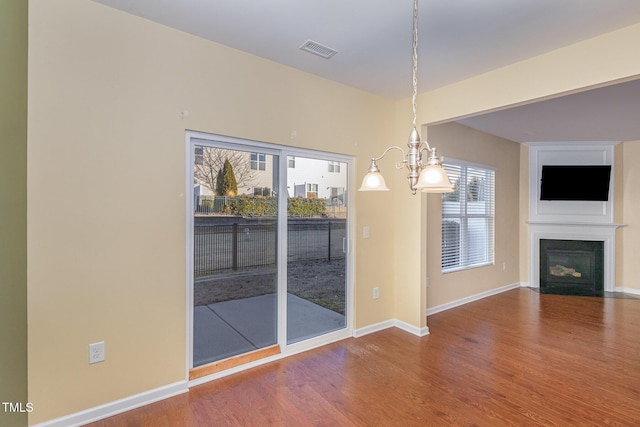 unfurnished dining area with wood-type flooring and an inviting chandelier