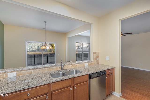 kitchen featuring sink, a wealth of natural light, stainless steel dishwasher, and light stone countertops