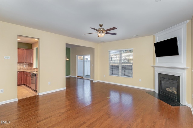 unfurnished living room featuring ceiling fan, sink, and light wood-type flooring