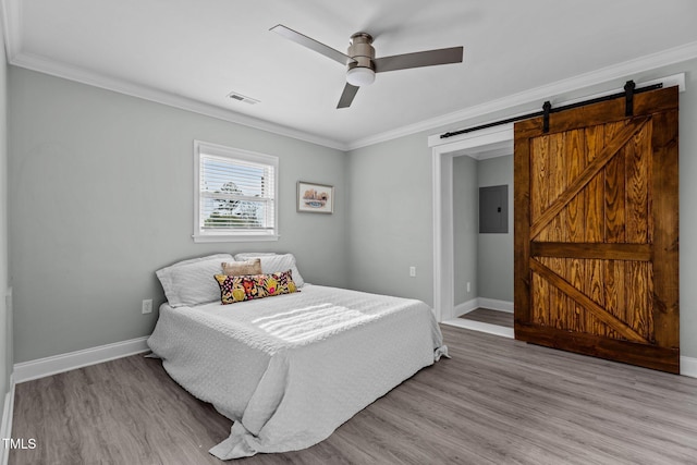 bedroom with crown molding, ceiling fan, electric panel, a barn door, and light wood-type flooring